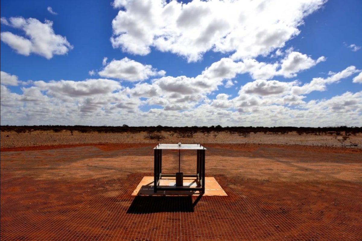 radio waves are collected by an antenna consisting of two rectangular metal panels mounted horizontally on fiberglass legs above a metal mesh.