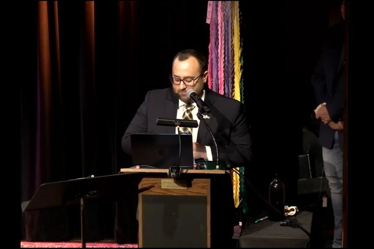 Man speaking into a microphone onstage.