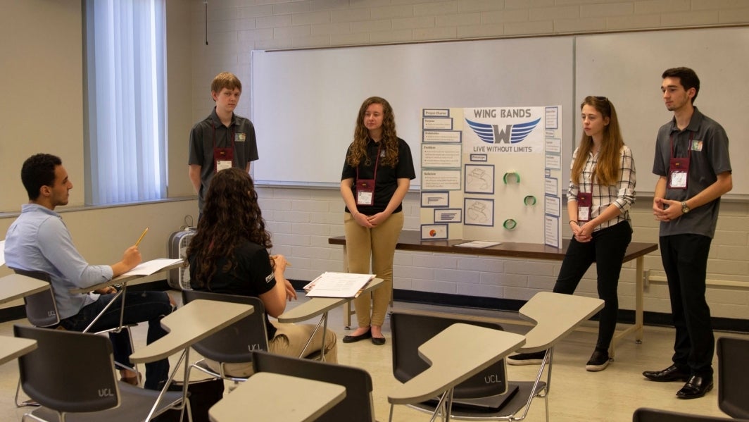 Seth Mazza (right) helps an EPICS High team he mentors present at an EPICS High showcase.