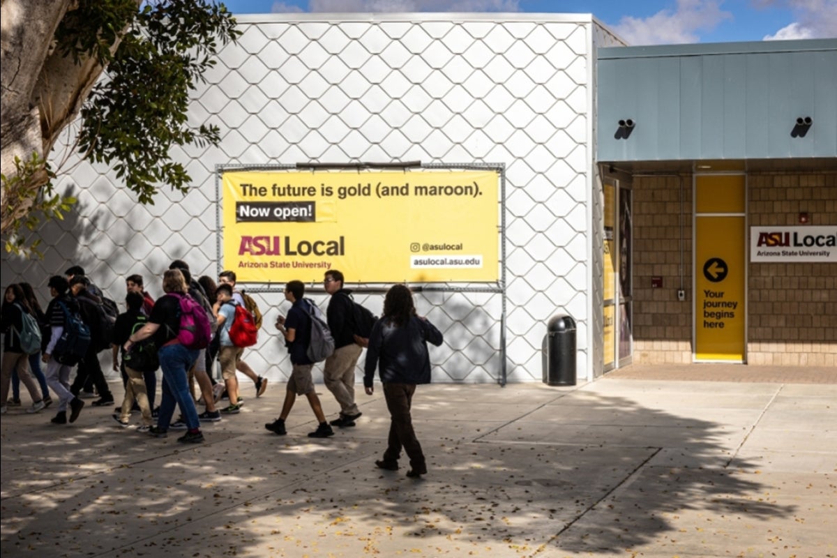 Students walking in front of an ASU Local sign on Arizona Western College campus