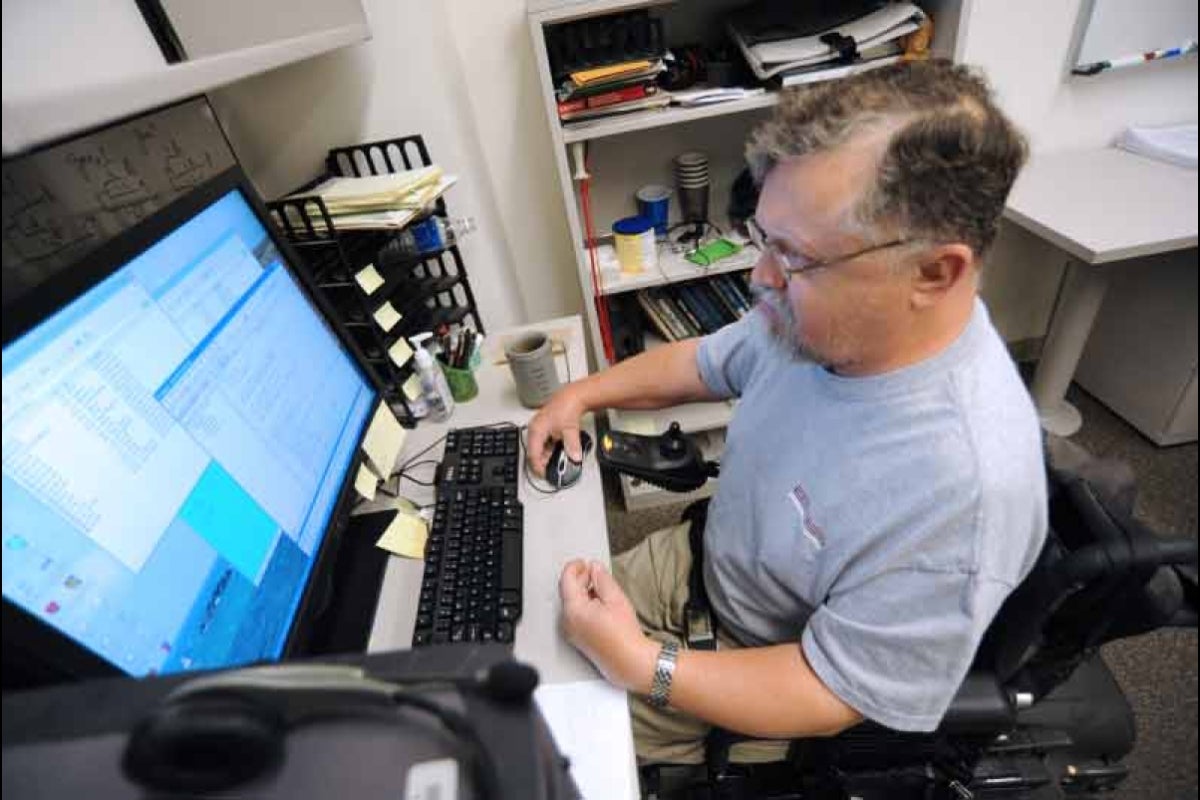 The late ASU researcher Alan Filipski sitting at his desk working on a computer.