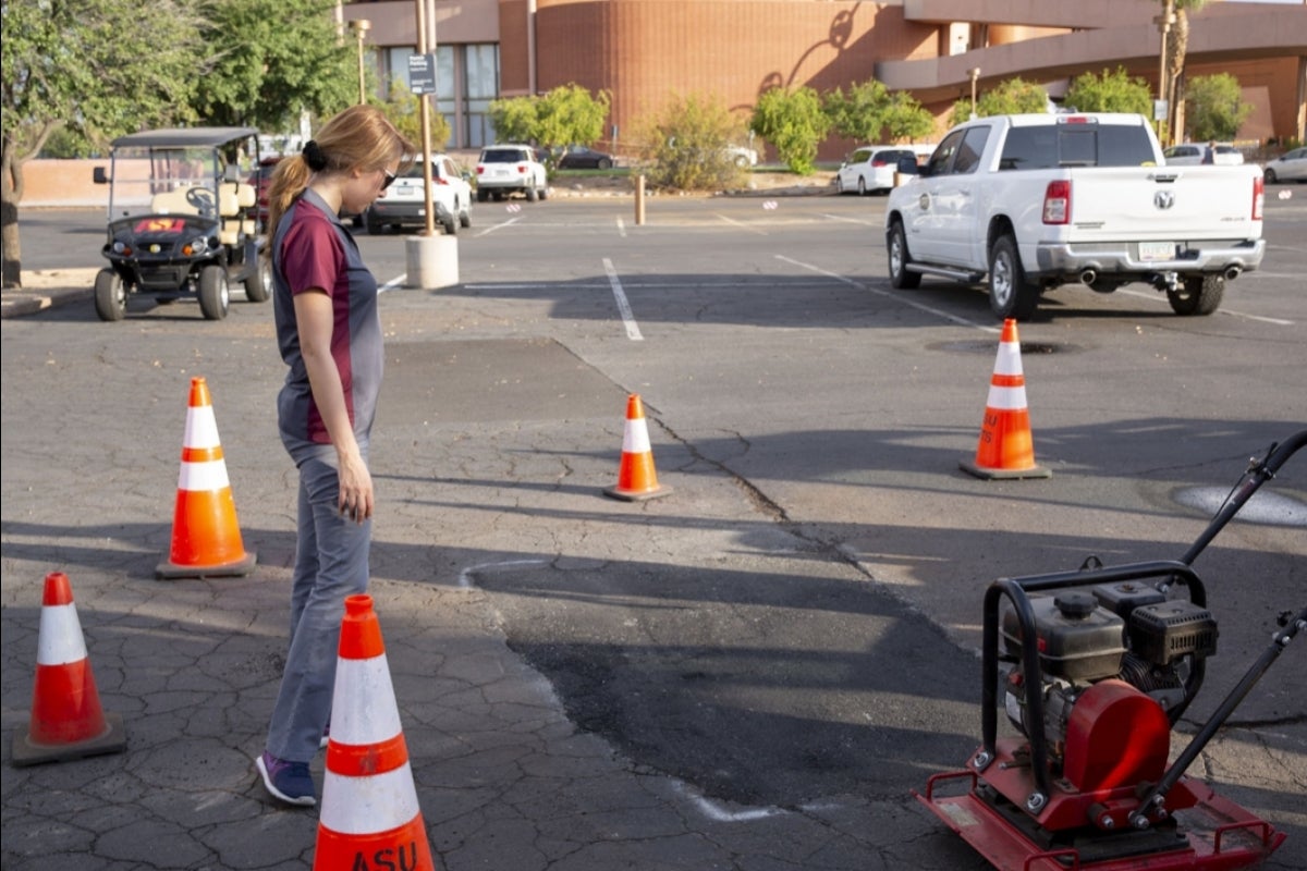 Woman looking at an asphalt patch in a parking lot.