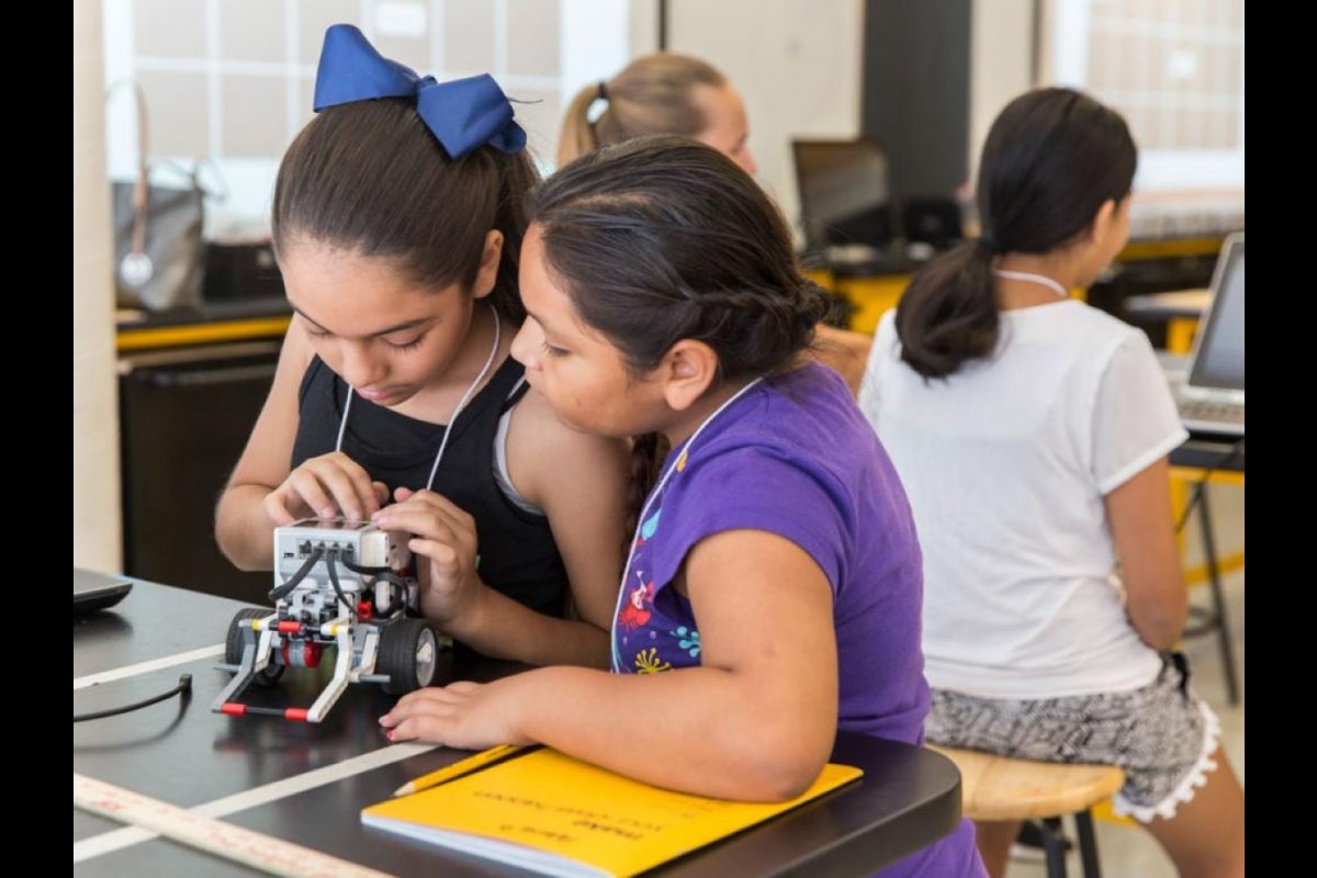 Two girls start up their robot to start testing their program.