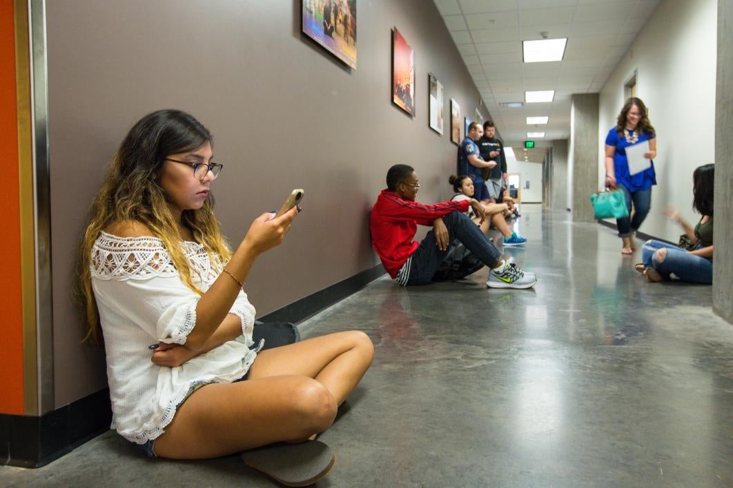 Student sitting in hallway looking at phone