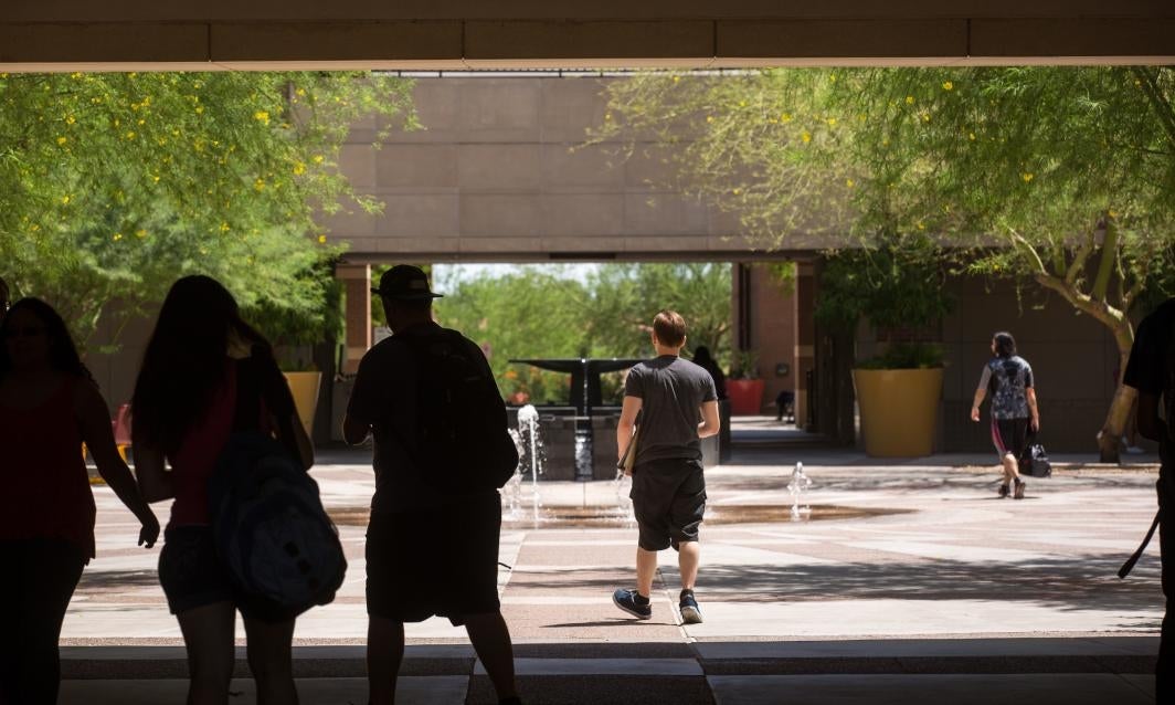 students walking by fountain across campus