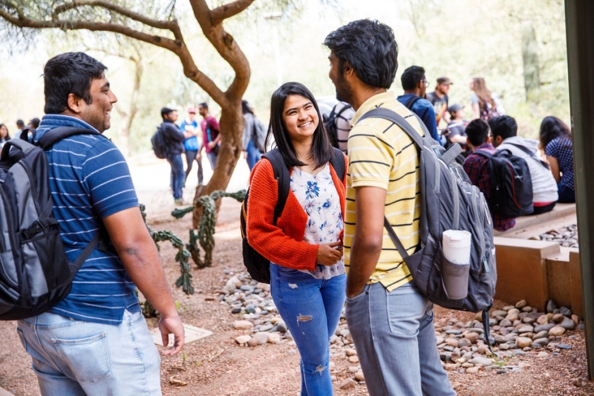 Students smile and talk outside