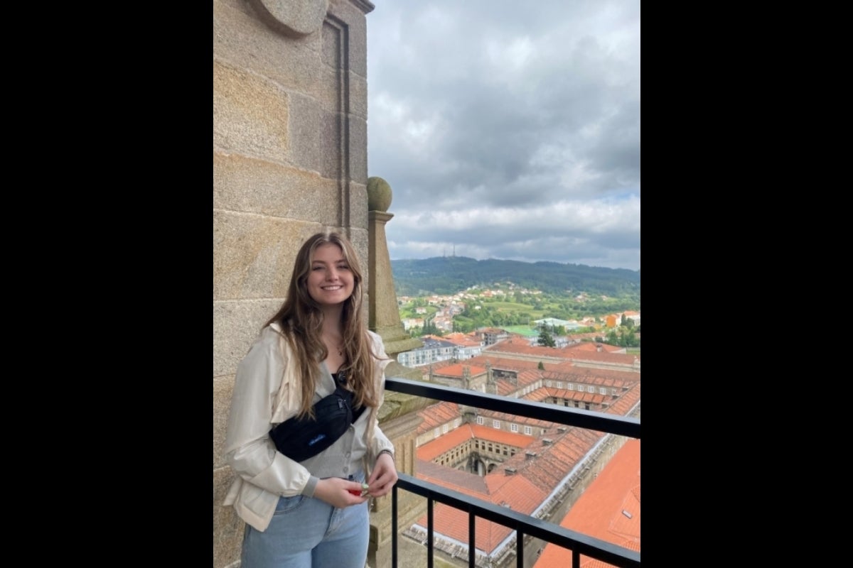 Woman standing next to a railng overlooking buildings in an old city in Spain.