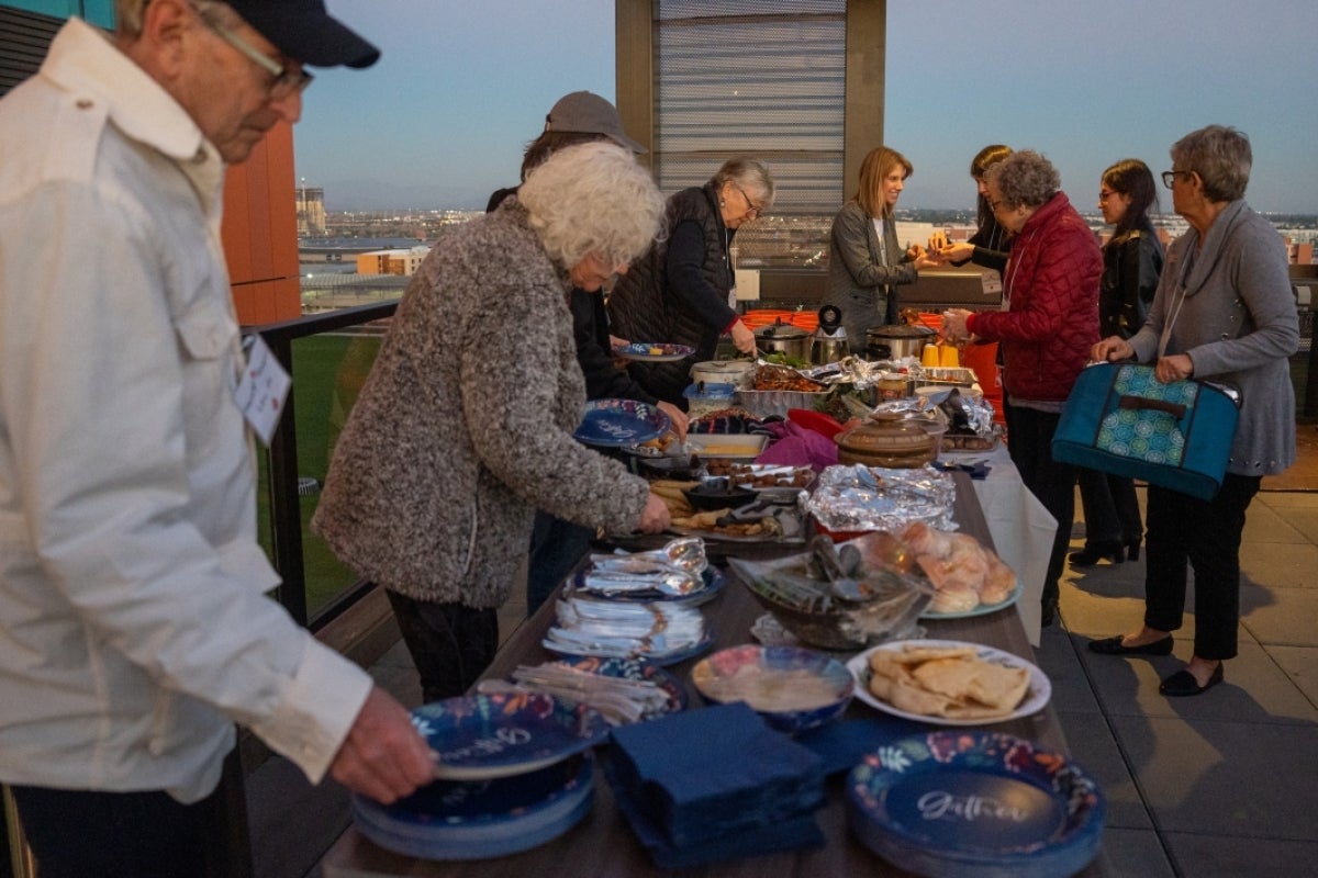 People lined up at a buffet dishing themselves food.