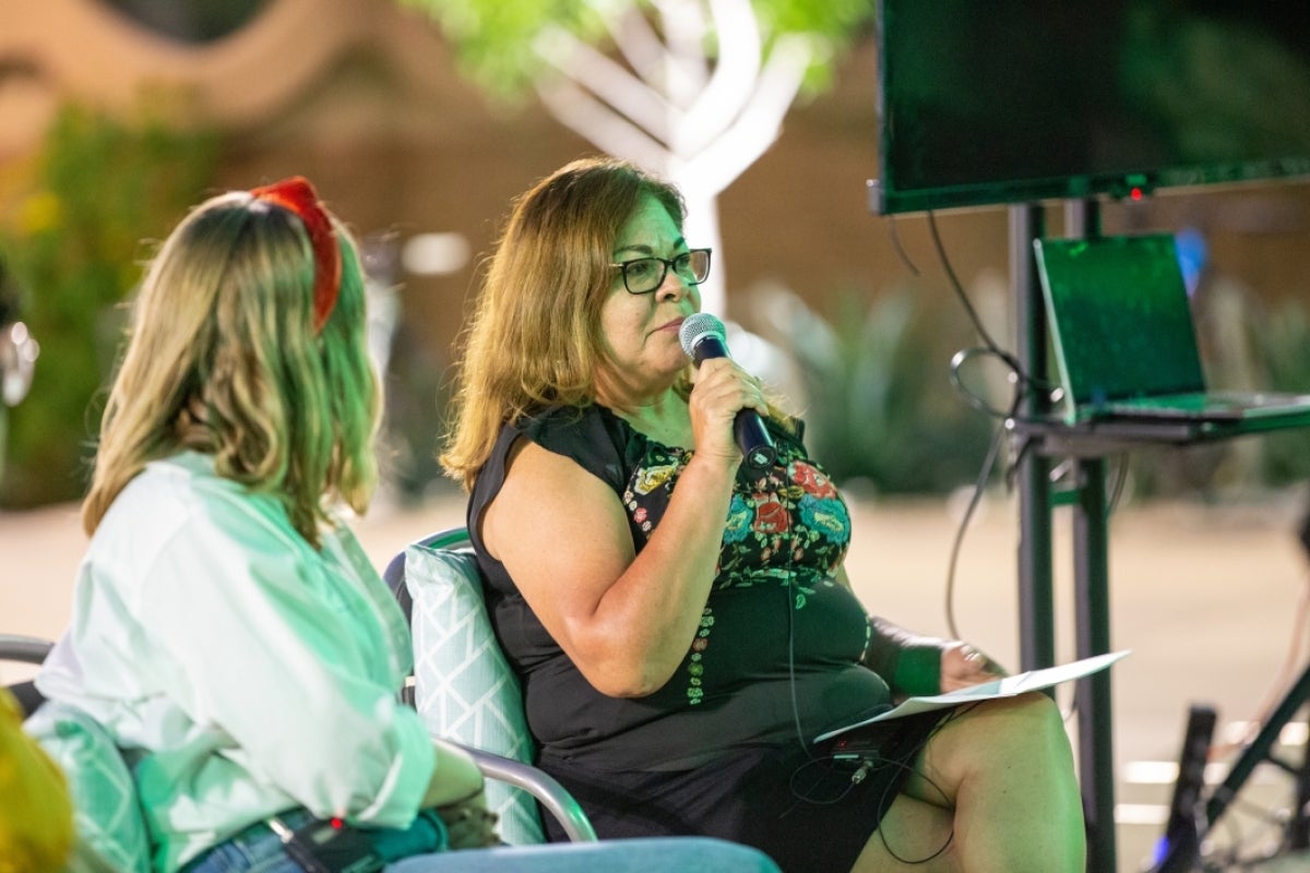 Woman seated while speaking into a microphone.