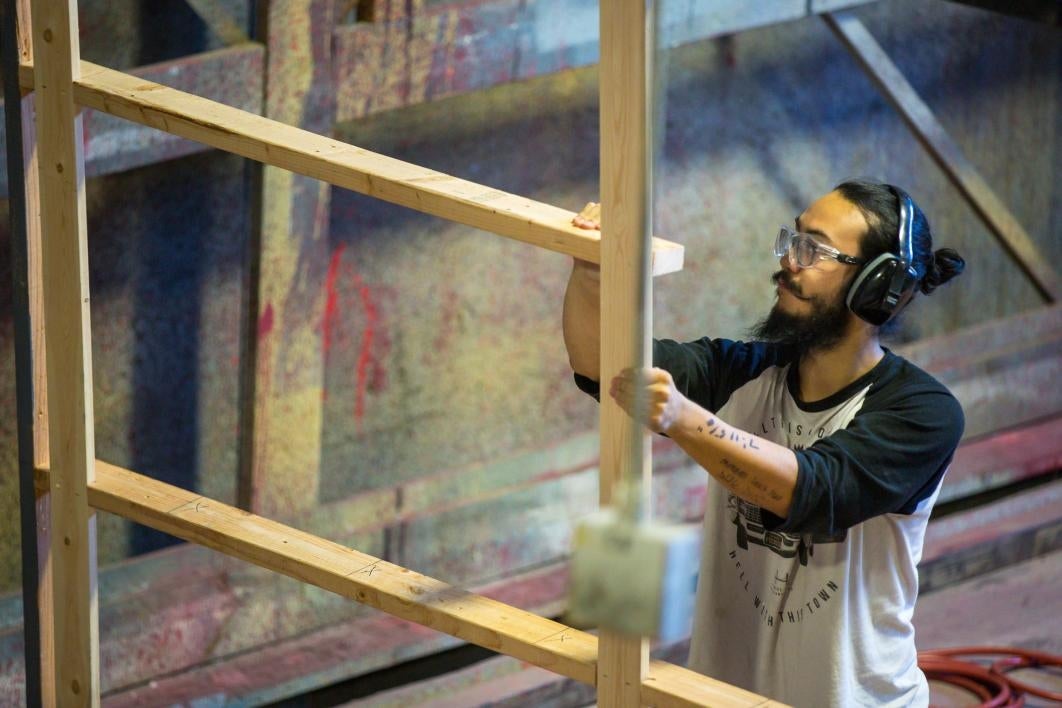 A student constructs a play's scenery.