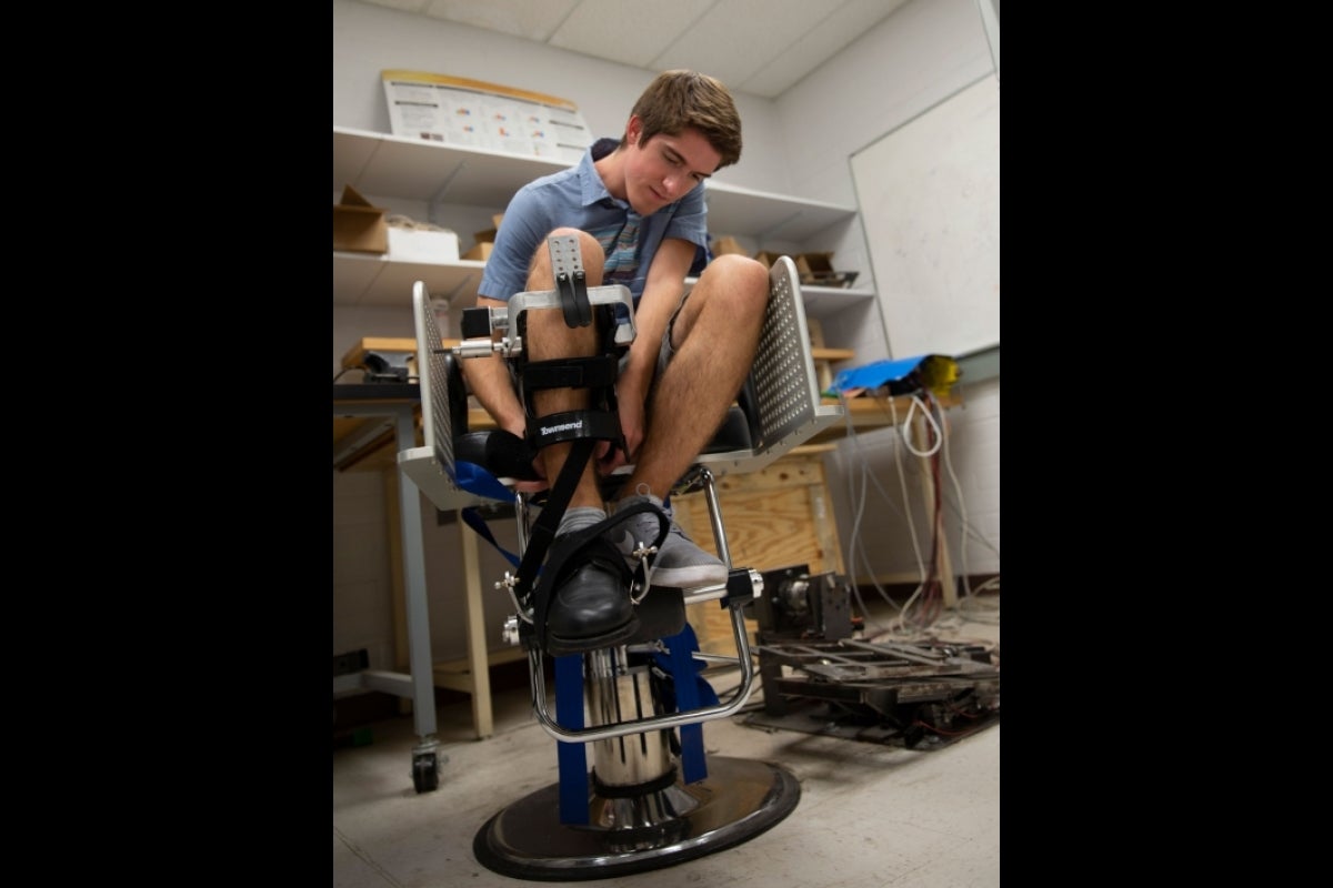 ASU alum James Arnold fastens a wearable soft robotics device to his leg.