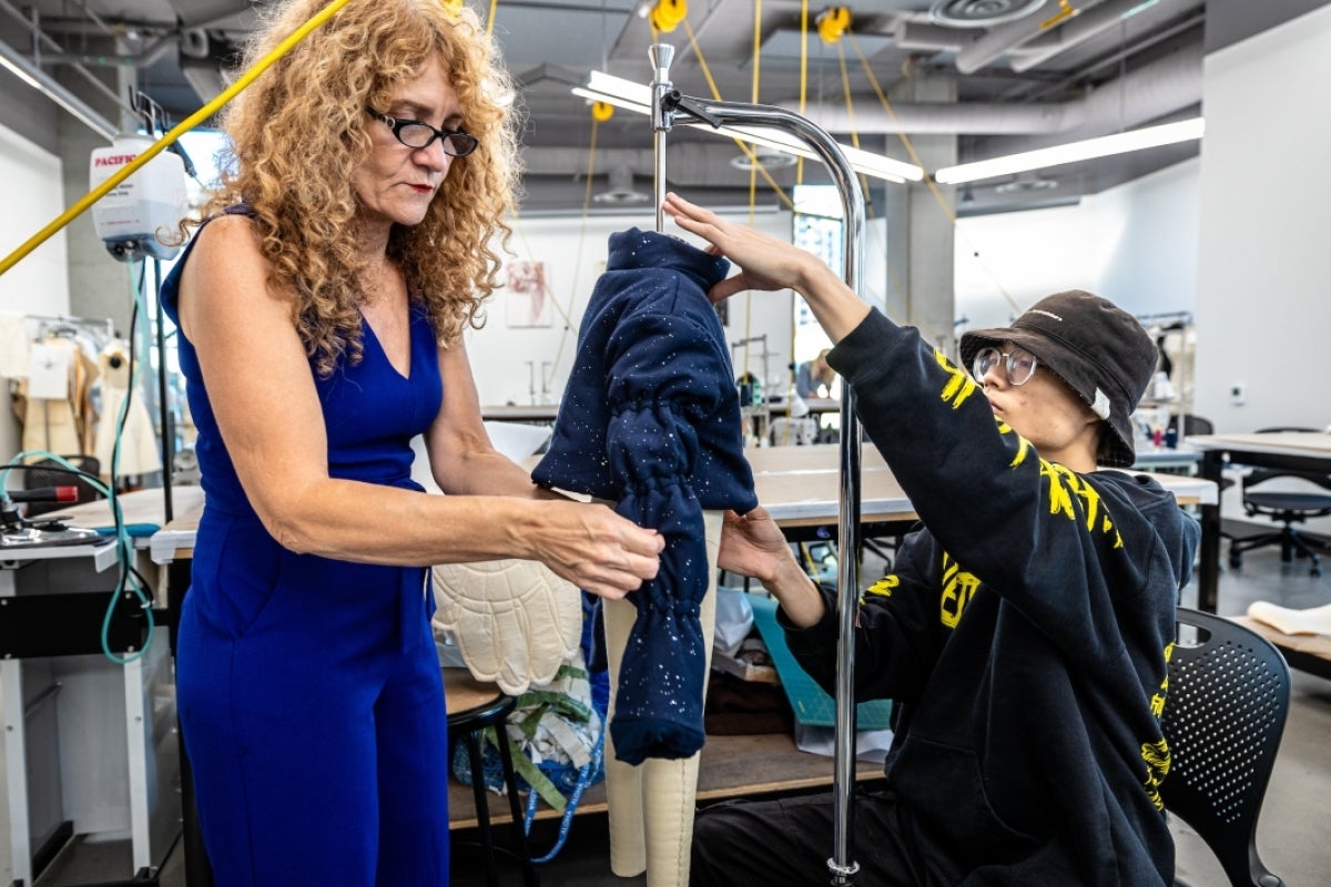 Person fitting a garment onto a mannequin.