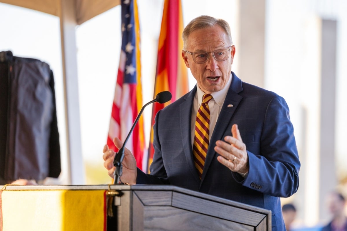 Man speaking into a microphone behind a lectern.