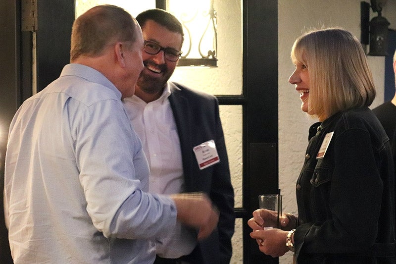 people wearing name tags, smiling and chatting at a networking event