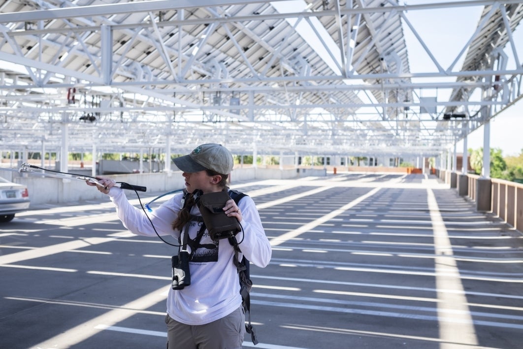 Postdoctoral researcher Kelsey McCune stands on an ASU parking structure listening to a radio receiver catching signals from a nearby bird with a radio tag backpack. McCune said reaching higher ground helps the signal become clearer.