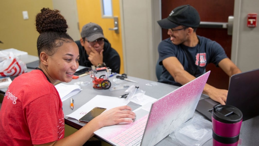 Students work on a robot and a laptop