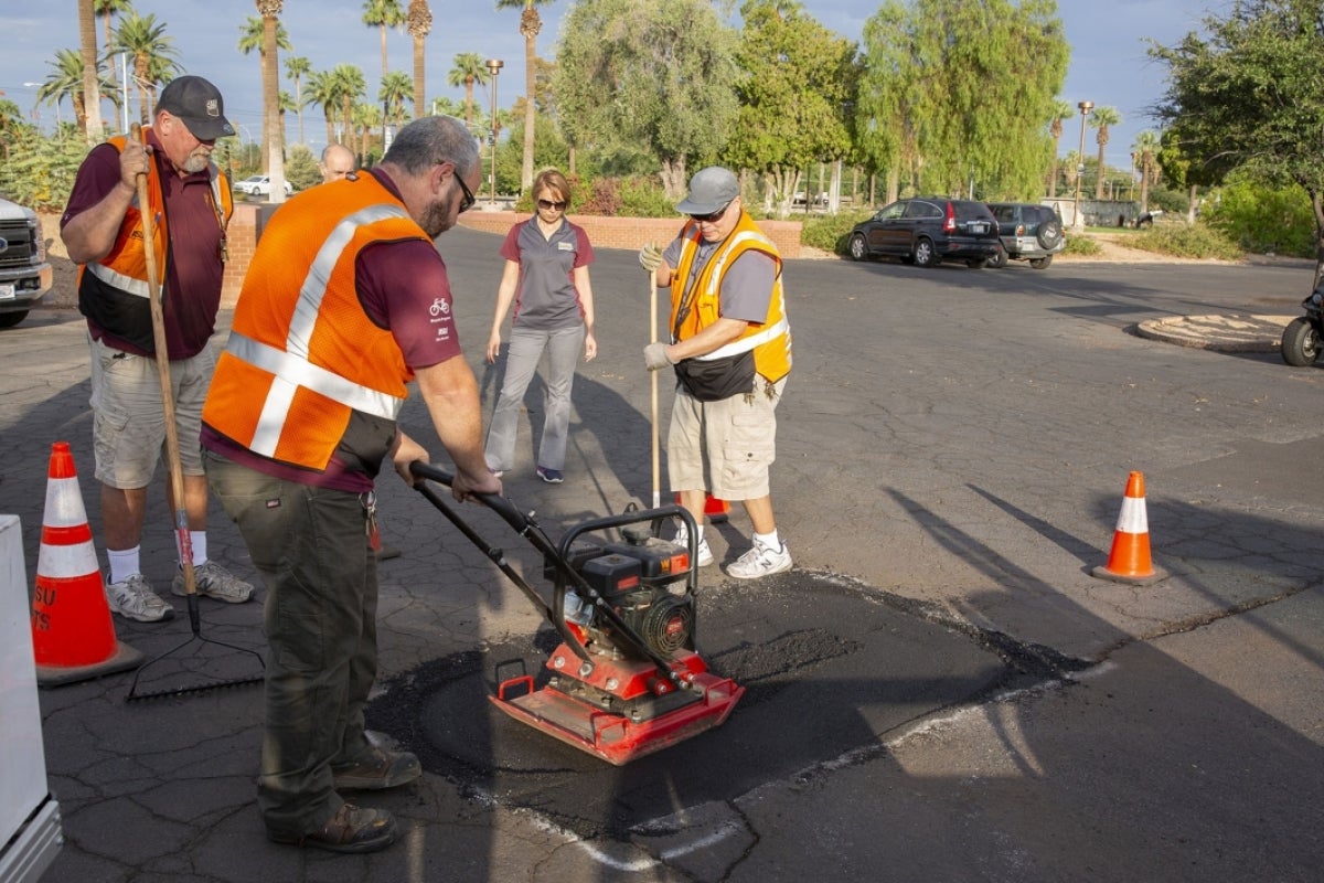 Workers apply AirDuo to patch an asphalt parking lot.