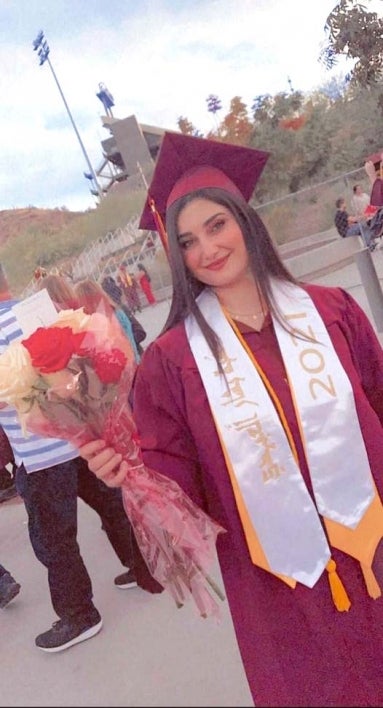 woman wearing cap and gown and holding flowers