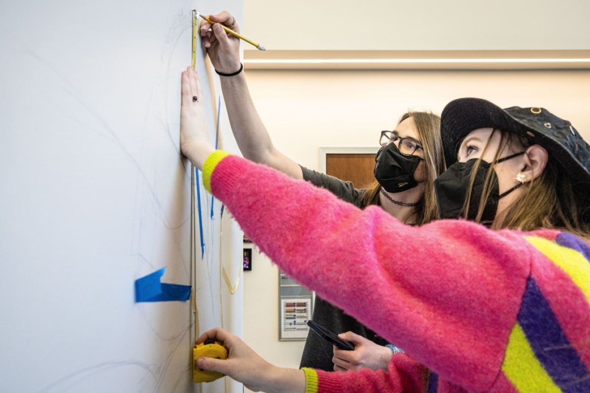 Two students drawing a mural.