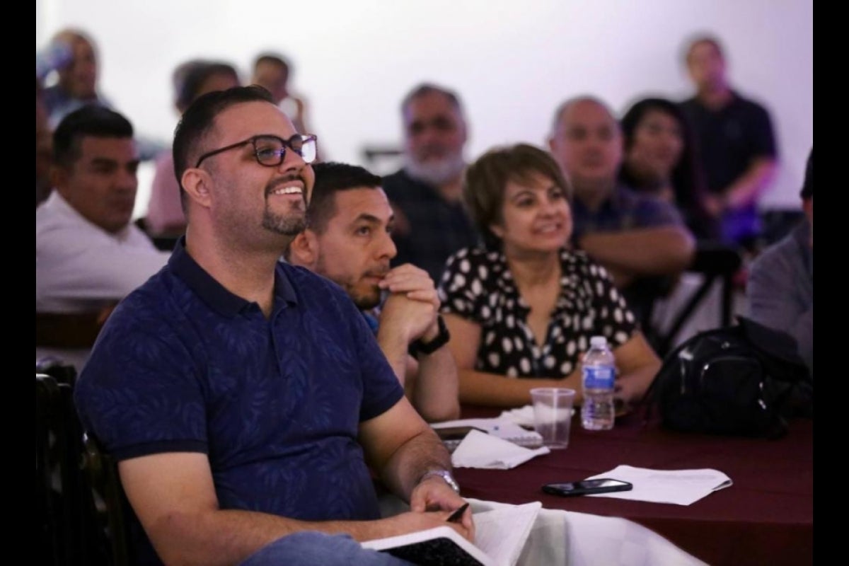 People seated in an audience listening and smiling.