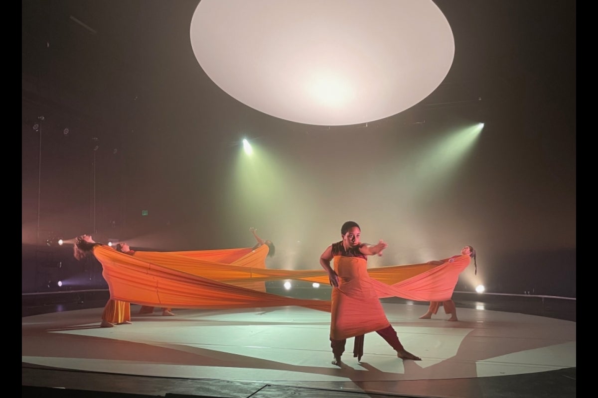 Performers wrapped in fabric and stretching it across stage.