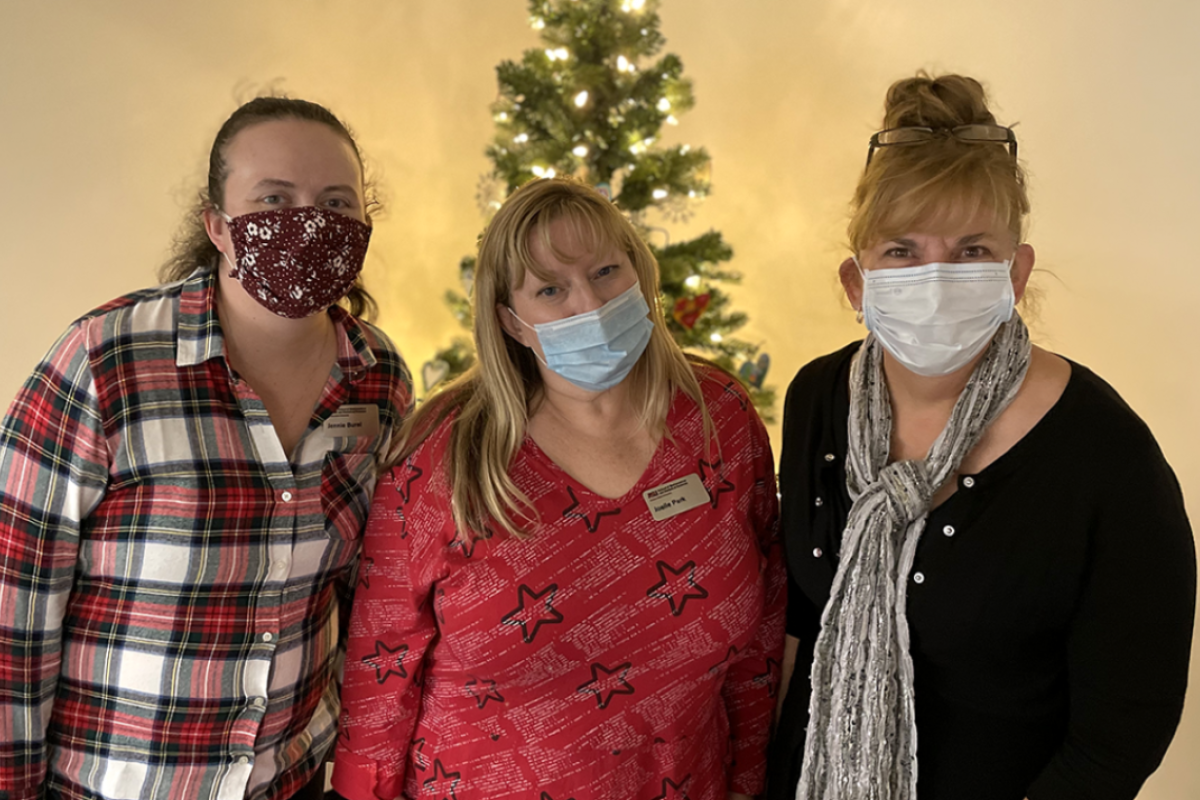 ASU staff Jennie Burel, Joelle Park and Sharon Crook stand in front of a Christmas tree in the SoMSS Graduate Office.