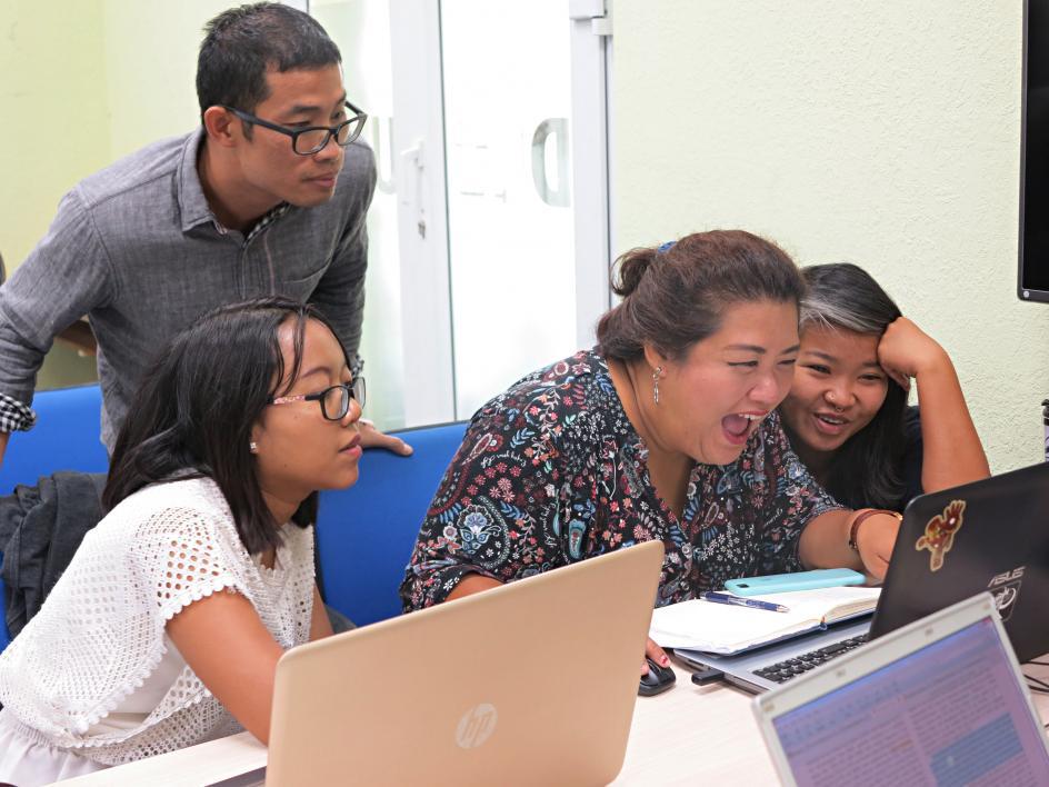 four people happy looking at a laptop