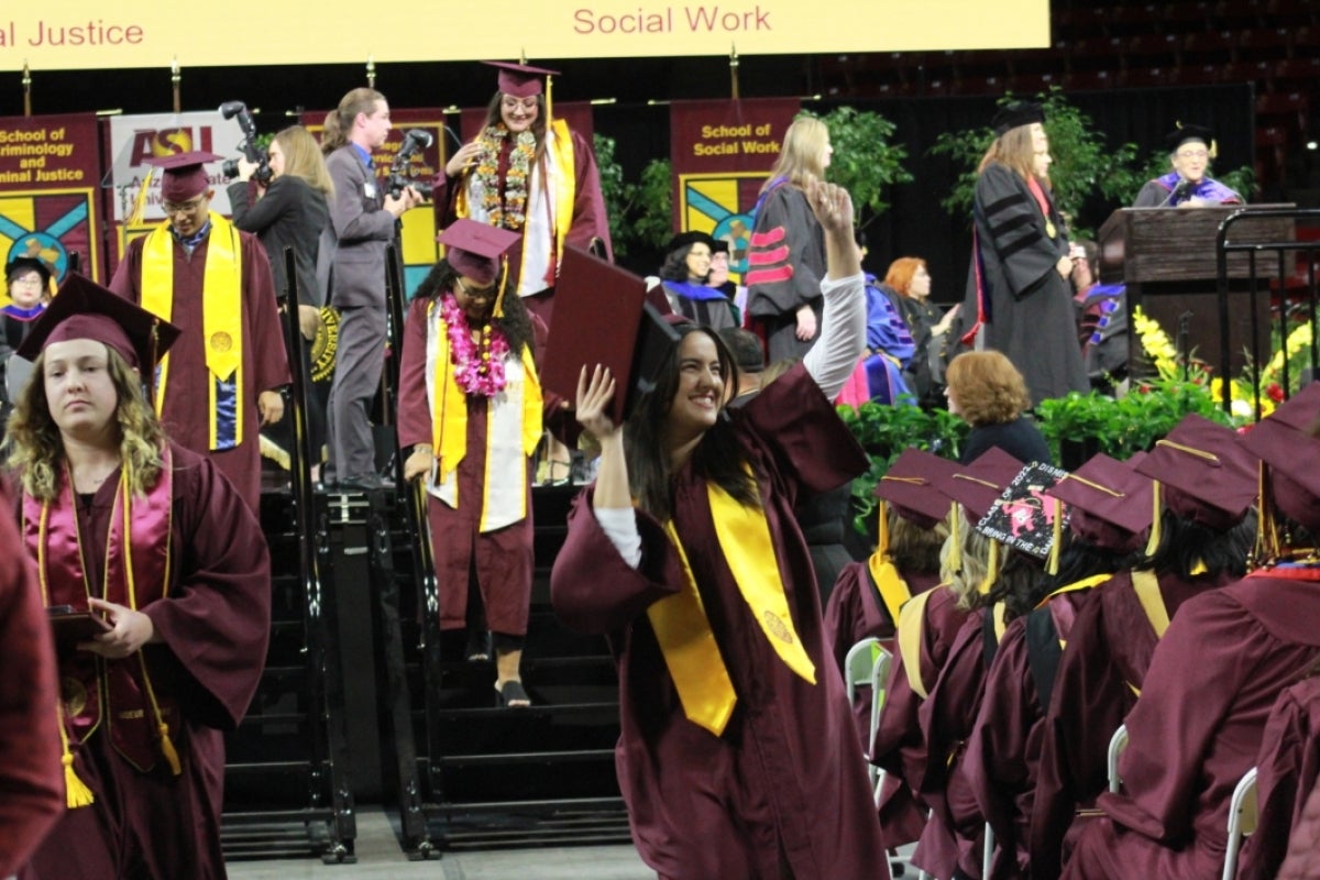 Watts College graduate waving to the crowd at graduation ceremony.