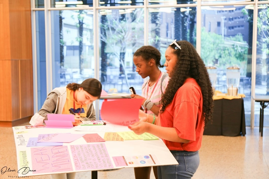 Three students prepare their presentation board