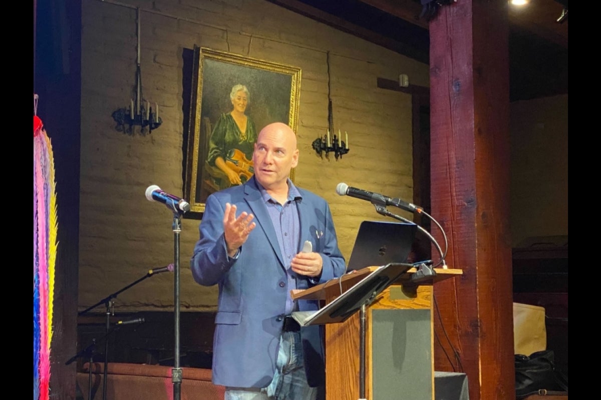 Man speaking into a microphone onstage.