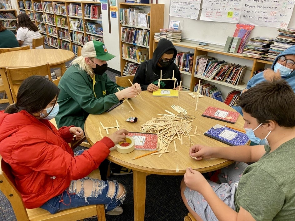 Emerson students sitting at a round table working on building dioramas.