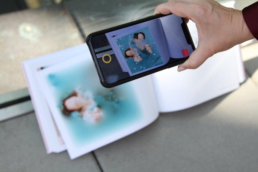 Hand holding a device in front of a book.