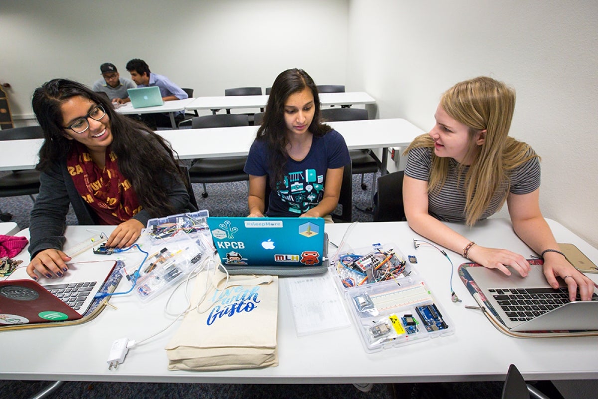 Three women work on computer board