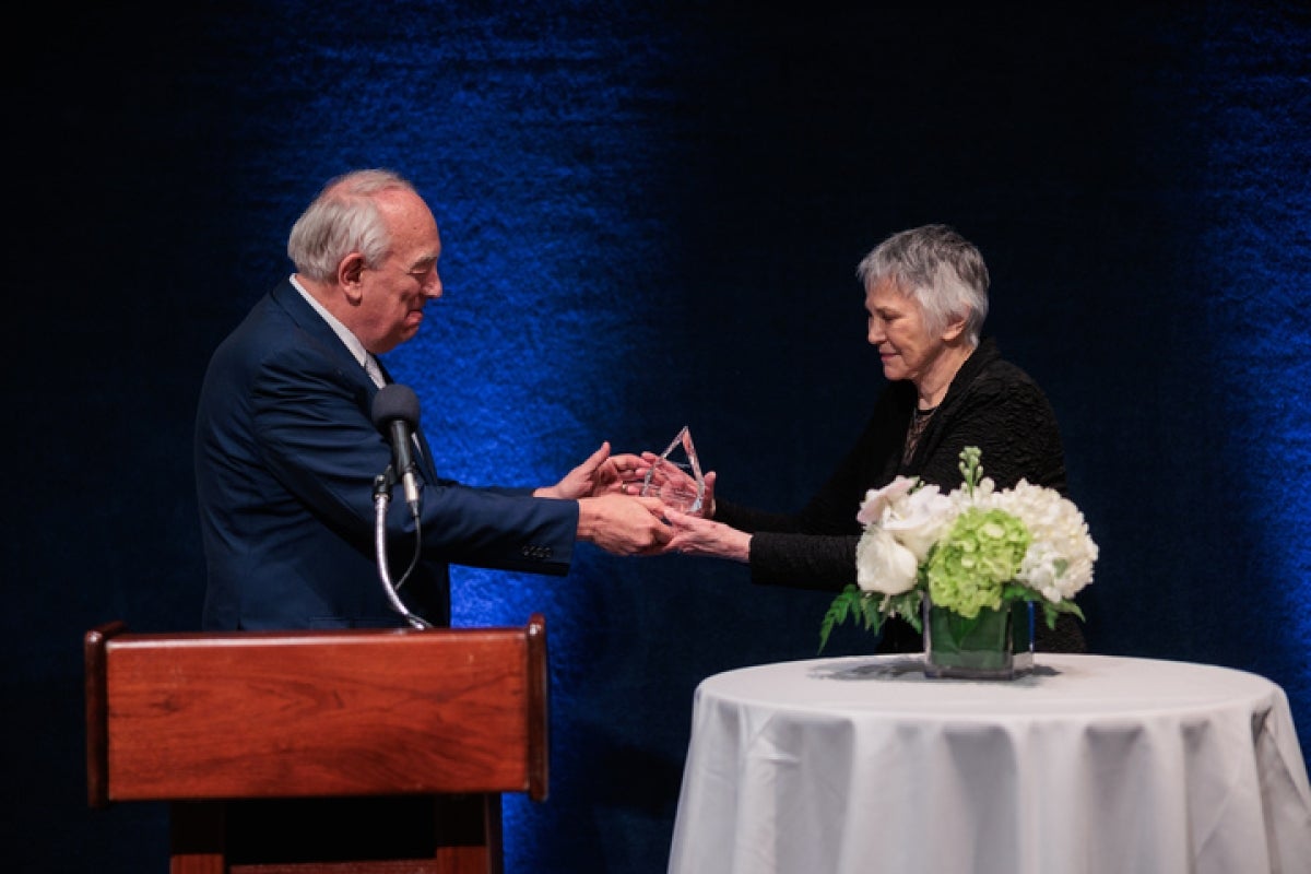 A man in a suit presents a woman with an award.