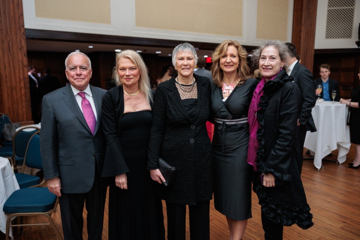 Men and women in suits and dresses pose for a picture.