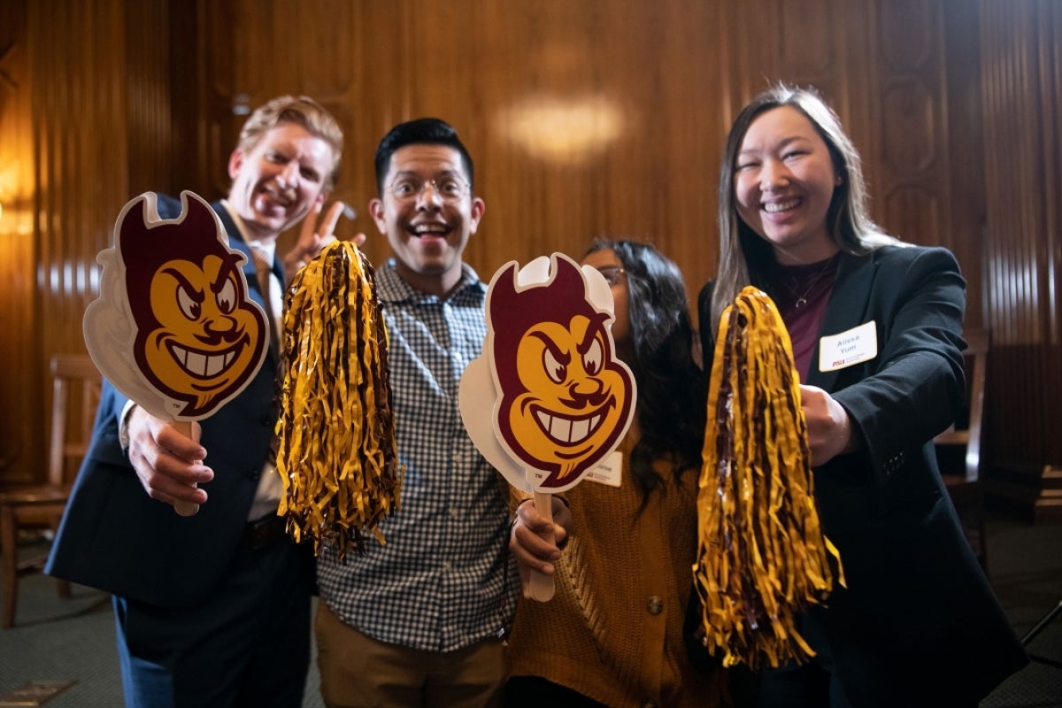 Student attendees hold up pom-poms and Sparky signs.