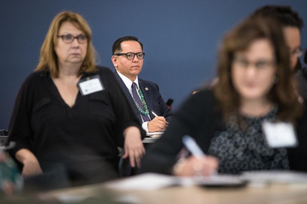 Man in glasses and tie listening to speaker