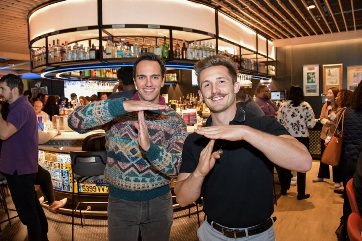 Attendees shown making a T symbol with their arms and hands at pub night.