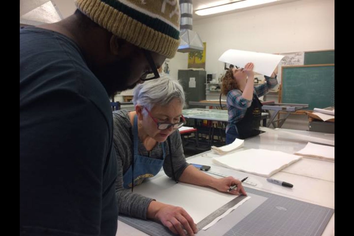 Artist Brenda Mallory works on her piece with students Jonathan Wright and Kelsey Reiman