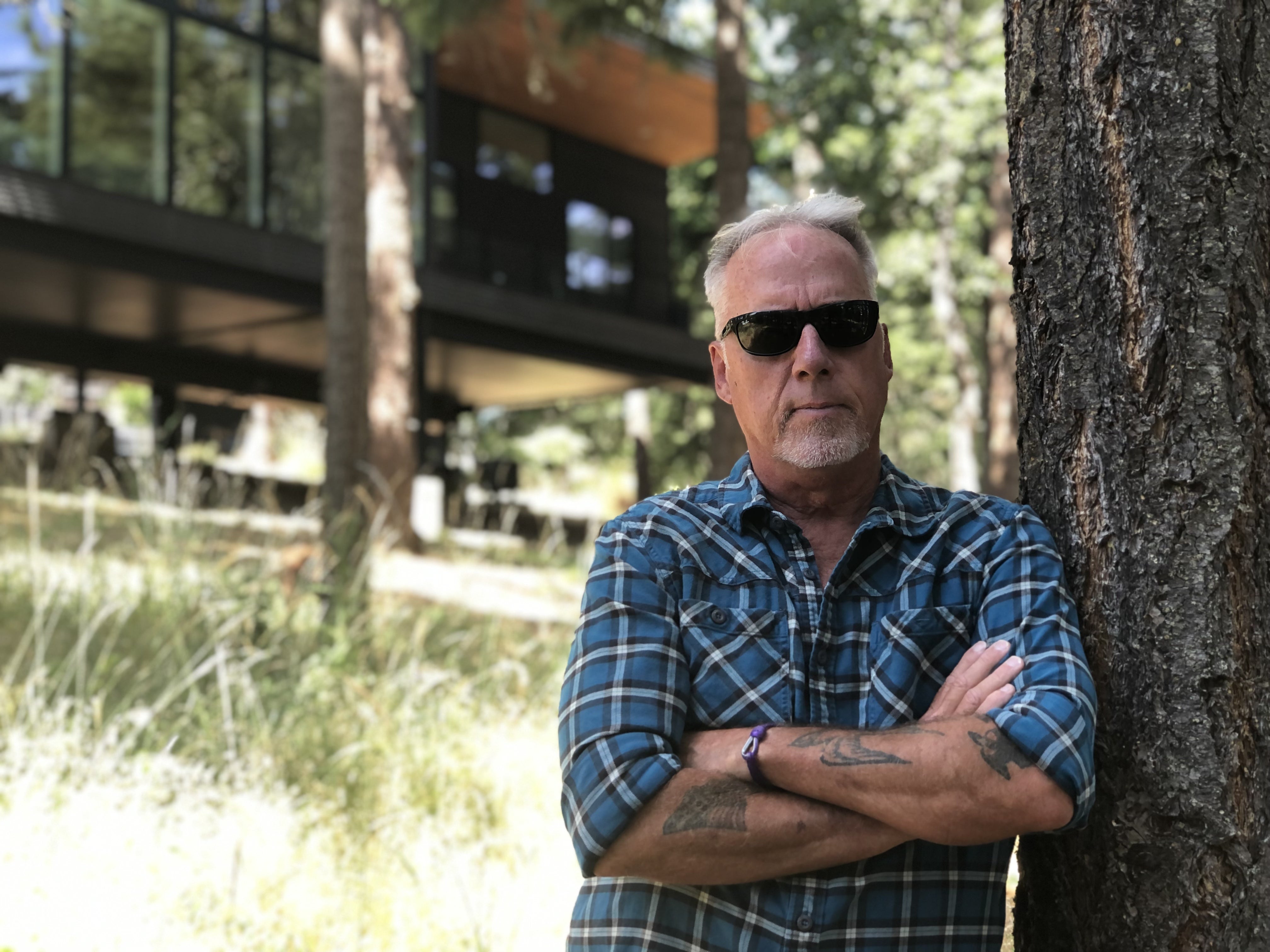 Man leaning on tree near house in forest