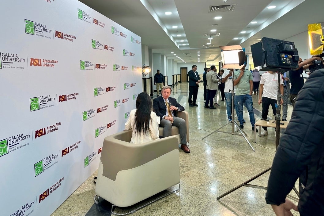 A woman interviews a man in front of video cameras