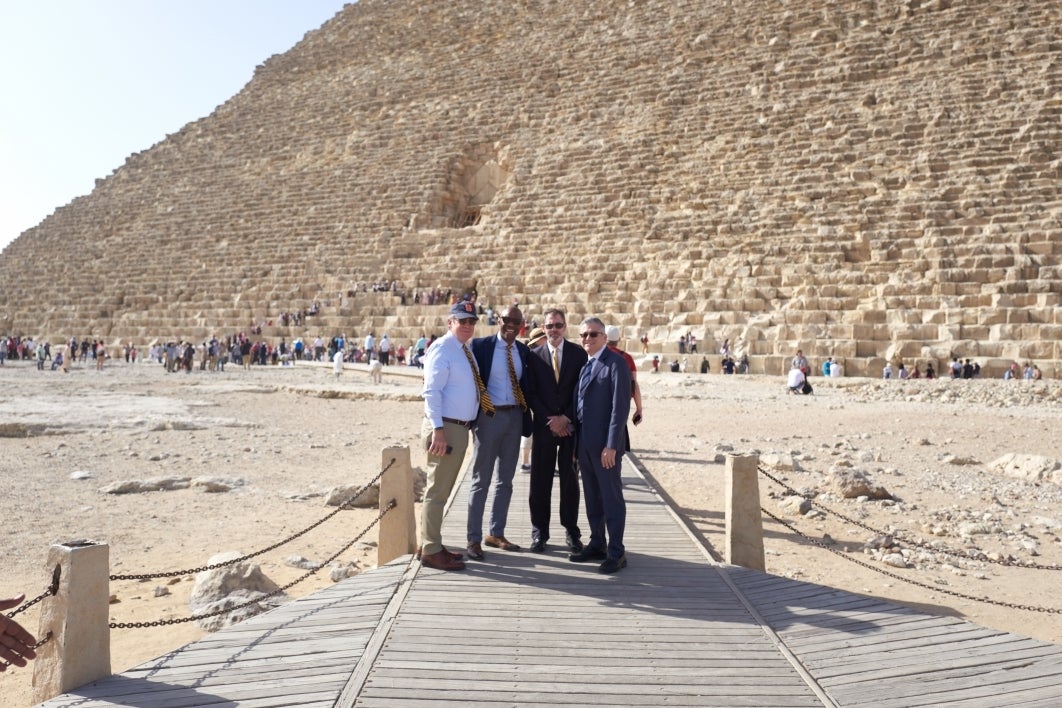 Four men pose in front of one of the pyramids in Egypt