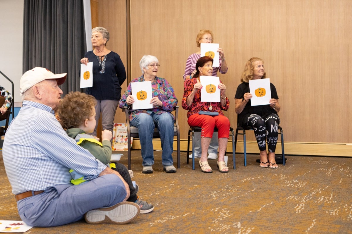 Mirabella at ASU students sitting in chairs, holding up pictures of pumpkins.