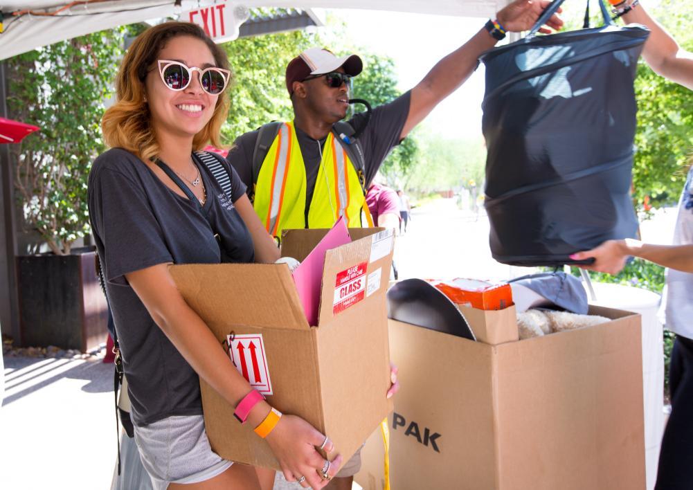 A new student smiles as she waits with her belongings to move into the downtown dorm.