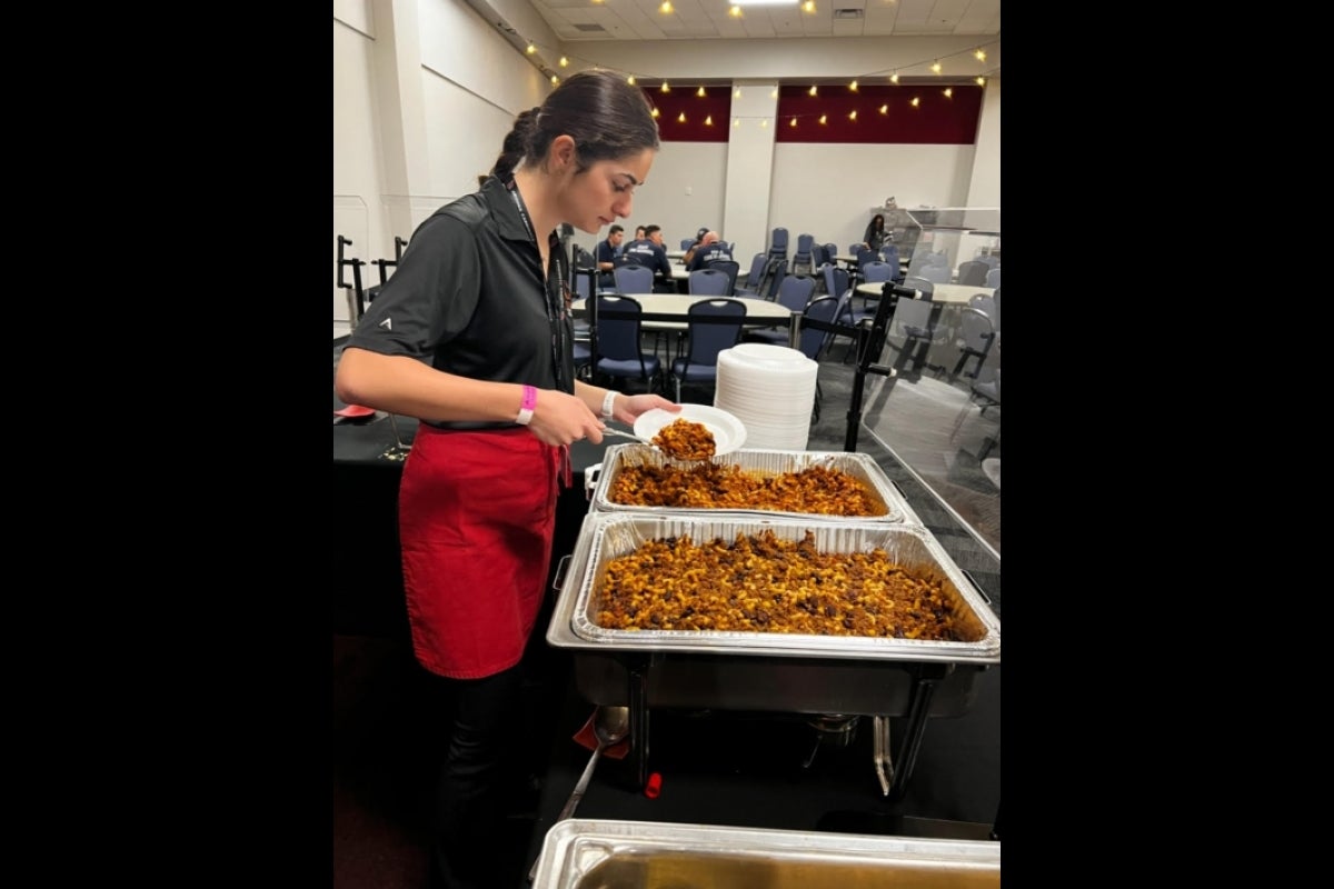 ASU student dishing food onto a plate.