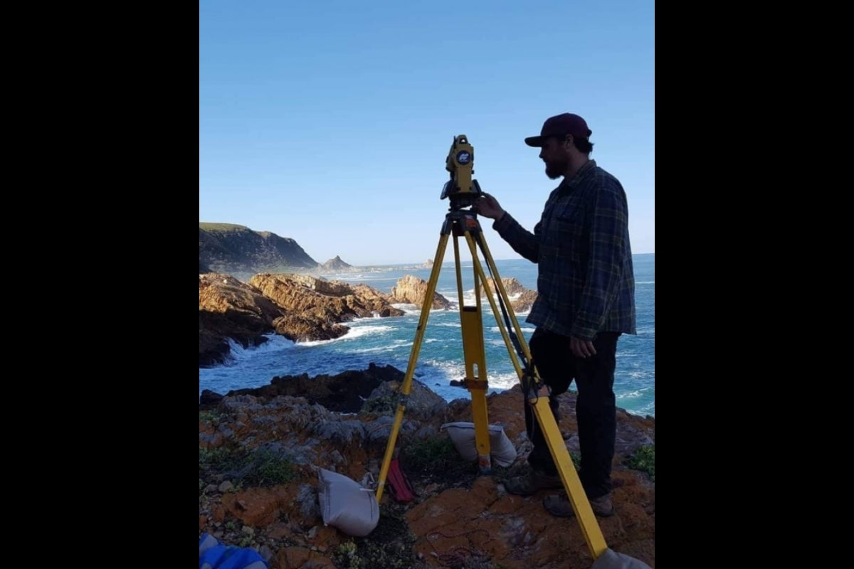  John using a total station on a coastal cliff recording the topography of the Knysna cave entrance.