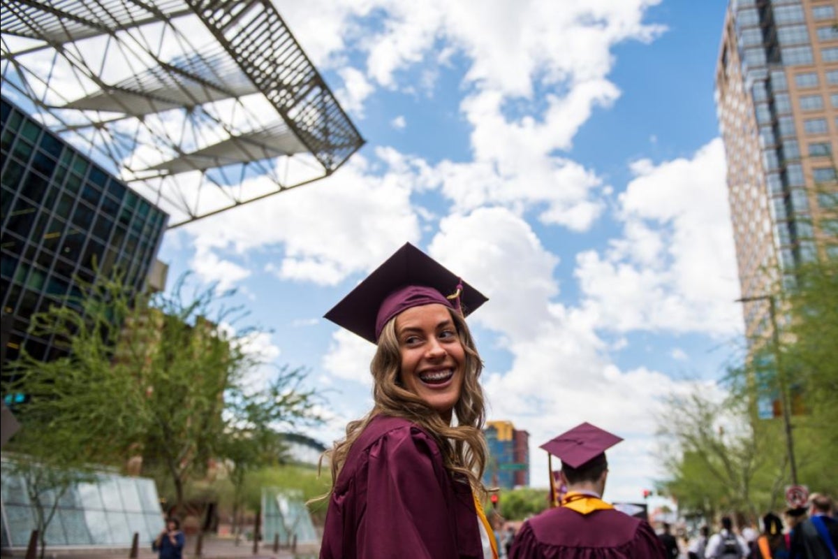 graduate in cap and gown looking over her shoulder