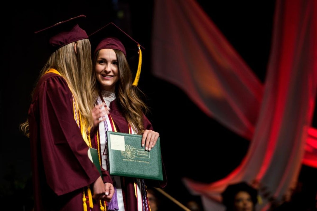 two graduates looking at each other at ceremony