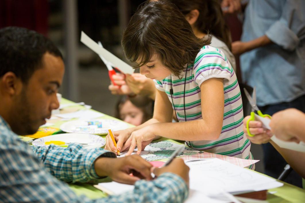 A little girl makes a paper bookmark.