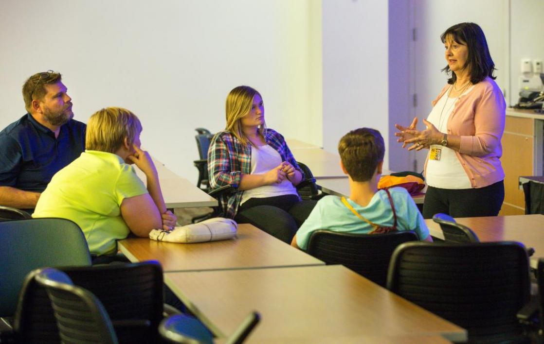 Adults talk in a classroom.